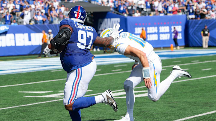 Sep 28, 2025; East Rutherford, New Jersey, USA; New York Giants defensive tackle Dexter Lawrence (97) is tackled by Los Angeles Chargers quarterback Justin Herbert (10) after intercepting a pass during the first half at MetLife Stadium. Mandatory Credit: Vincent Carchietta-Imagn Images