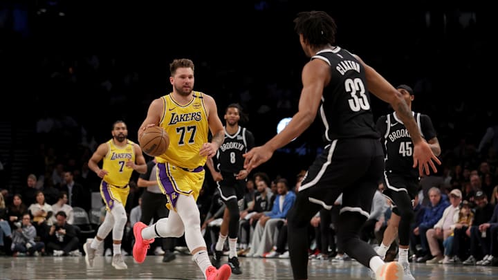 Mar 10, 2025; Brooklyn, New York, USA; Los Angeles Lakers guard Luka Doncic (77) brings the ball up court against Brooklyn Nets forward Ziaire Williams (8) and guard Keon Johnson (45) and center Nic Claxton (33) during the first quarter at Barclays Center. Mandatory Credit: Brad Penner-Imagn Images