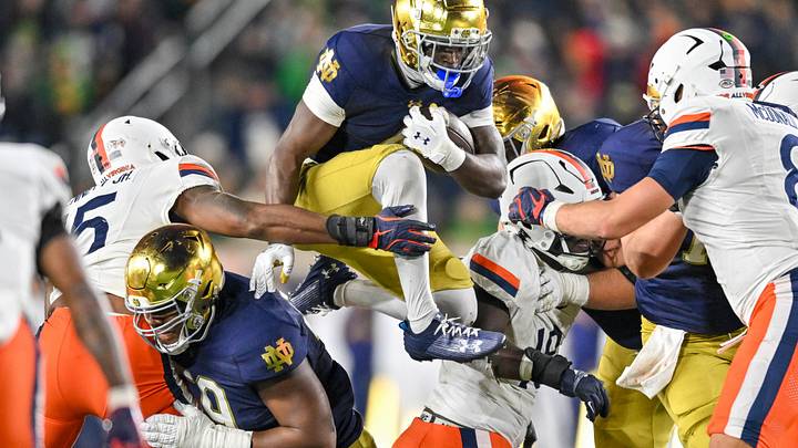 Nov 16, 2024; South Bend, Indiana, USA; Notre Dame Fighting Irish running back Jeremiyah Love (4) jumps over defenders against the Virginia Cavaliers in the fourth quarter at Notre Dame Stadium. Mandatory Credit: Matt Cashore-Imagn Images Nov 16, 2024; South Bend, Indiana, USA; Notre Dame Fighting Irish running back Jeremiyah Love (4) jumps over defenders against the Virginia Cavaliers in the fourth quarter at Notre Dame Stadium. Mandatory Credit: Matt Cashore-Imagn Images