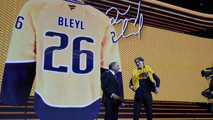 Jun 26, 2026; Buffalo, New York, USA; Tommy Bleyl reacts beside NHL commissioner Gary Bettman after being selected with the thirty first pick in the first round of the 2026 NHL Draft by the Nashville Predators at KeyBank Center. Mandatory Credit: Timothy T. Ludwig-Imagn Images