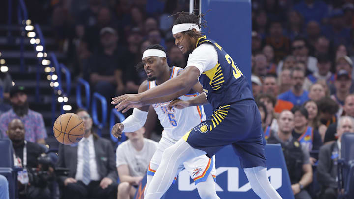 Mar 29, 2025; Oklahoma City, Oklahoma, USA; Indiana Pacers center Myles Turner (33) and Oklahoma City Thunder guard Luguentz Dort (5) reach for a loose ball during the first quarter at Paycom Center. Mandatory Credit: Alonzo Adams-Imagn Images