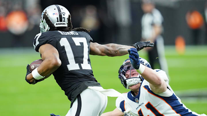 Jan 7, 2024; Paradise, Nevada, USA; Las Vegas Raiders wide receiver Davante Adams (17) stiff-arms Denver Broncos linebacker Drew Sanders (41) during the second quarter at Allegiant Stadium. Mandatory Credit: Stephen R. Sylvanie-Imagn Images