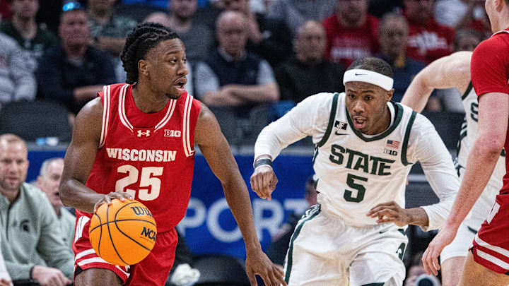 Mar 15, 2025; Indianapolis, IN, USA; Wisconsin Badgers guard John Blackwell (25) dribbles the ball while Michigan State Spartans guard Tre Holloman (5) defends in the first half at Gainbridge Fieldhouse. Mandatory Credit: Trevor Ruszkowski-Imagn Images