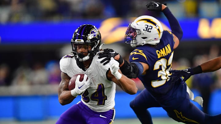 Baltimore Ravens running back Keaton Mitchell (34) runs the ball ahead of Los Angeles Chargers safety Alohi Gilman (32) during the first half at SoFi Stadium. 