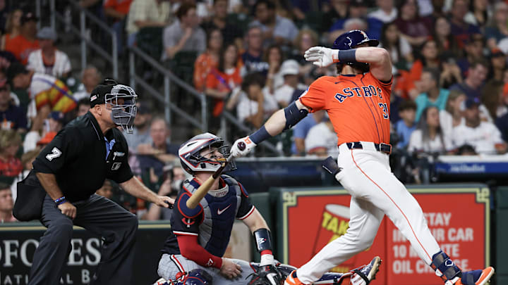 A baseball player in an orange and white uniform swinging a brown bat in front of an umpire and catcher. A baseball player in an orange and white uniform swinging a brown bat in front of an umpire and catcher.
