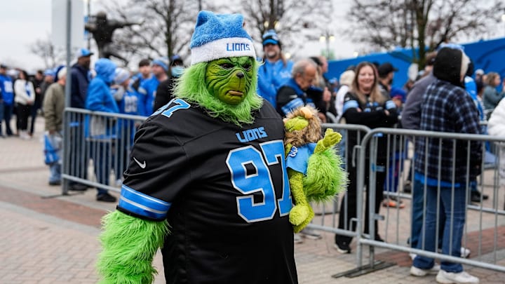 A Detroit Lions fan dresses as Grinch walk by fans in line before the game between Detroit Lions and Buffalo Bills at Ford Field in Detroit on Sunday, Dec. 15, 2024.