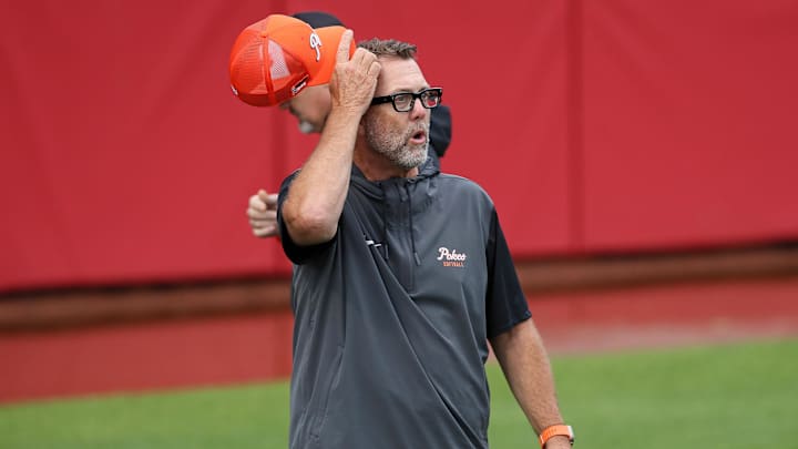 May 18, 2025; Fayetteville, AR, USA; Oklahoma State Cowgirls head coach Kenny Gajewski assesses the water in the outfield while discussing a time to begin the regional final game against the Arkansas Razorbacks, that has multiple delays due weather. Mandatory Credit: Nelson Chenault-Imagn Images