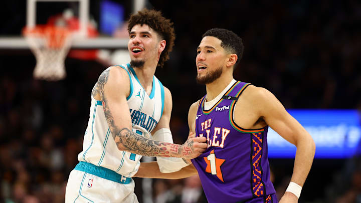 Jan 12, 2025; Phoenix, Arizona, USA; Charlotte Hornets guard LaMelo Ball (1) reacts with Phoenix Suns guard Devin Booker (1) during the first half at Footprint Center. Mandatory Credit: Mark J. Rebilas-Imagn Images