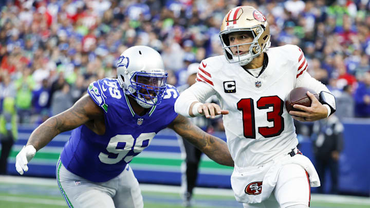 Oct 10, 2024; Seattle, Washington, USA; San Francisco 49ers quarterback Brock Purdy (13) rushes with Seattle Seahawks defensive end Leonard Williams (99) in pursuit during the first quarter at Lumen Field.