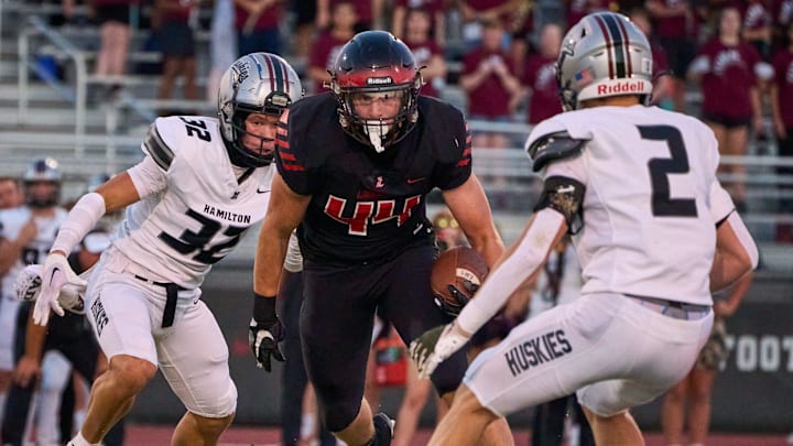 Liberty Lions senior tight end Ryan Wolfer (44) runs the ball against Hamilton Huskies sophomore linebacker Beau Jandreau (32) and senior free safety Jackson Finefrock (2) at Liberty High School in Peoria, on Friday, Aug. 25, 2023.