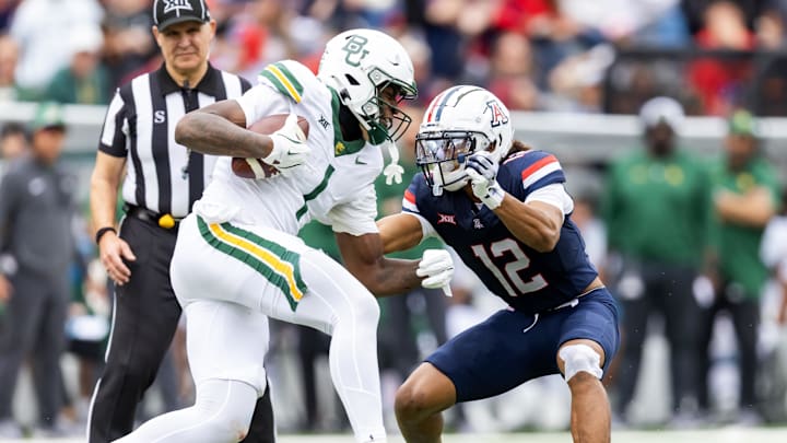 Nov 22, 2025; Tucson, Arizona, USA; Arizona Wildcats defensive back Genesis Smith (12) tackles Baylor Bears tight end Michael Trigg (1) at Casino Del Sol Stadium. Mandatory Credit: Mark J. Rebilas-Imagn Images