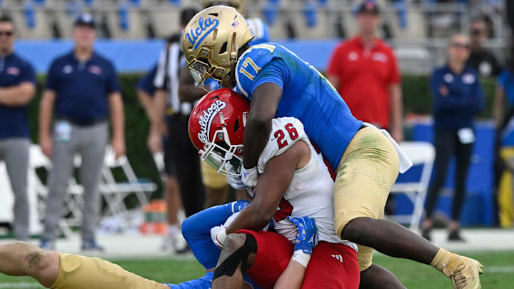 Nov 30, 2024; Pasadena, California, USA; UCLA Bruins linebackers Carson Schwesinger (49) and Jalen Woods (17) tackle Fresno State Bulldogs running back Bryson Donelson (26) during the third quarter at Rose Bowl. Mandatory Credit: Robert Hanashiro-Imagn Images