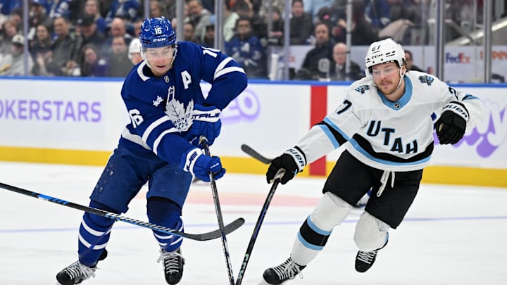 Nov 24, 2024; Toronto, Ontario, CAN;  Toronto Maple Leafs forward Mitch Marner (16) stickhandles the puck past Utah Hockey Club forward Barrett Hayton (27) in the third period at Scotiabank Arena. Mandatory Credit: Dan Hamilton-Imagn Images