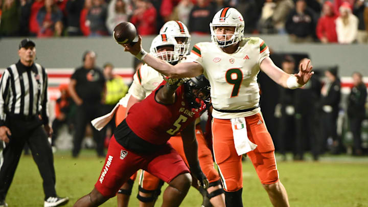 Nov 4, 2023; Raleigh, North Carolina, USA; Miami Hurricanes quarterback Tyler Van Dyke (9) throws a pass as he is pressured by North Carolina State Wolfpack defensive tackle CJ Clark (5) during the second half at Carter-Finley Stadium.  Mandatory Credit: Rob Kinnan-USA TODAY Sports