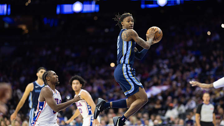 Memphis Grizzlies guard Ja Morant (12) leaps to catch a pass in front of Philadelphia 76ers guard Tyrese Maxey (0) during the fourth quarter at Wells Fargo Center. Mandatory Credit: Bill Streicher-Imagn Images