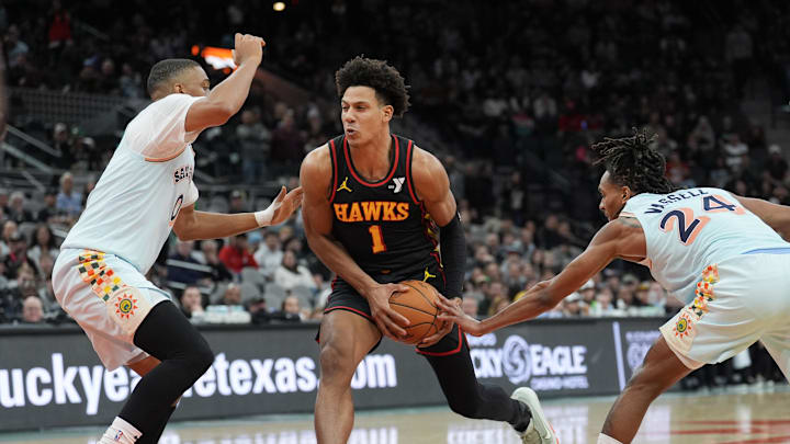 Dec 19, 2024; San Antonio, Texas, USA;  Atlanta Hawks forward Jalen Johnson (1) drives in between San Antonio Spurs forward Keldon Johnson (0) and guard Devin Vassell (24) in overtime at Frost Bank Center. Mandatory Credit: Daniel Dunn-Imagn Images