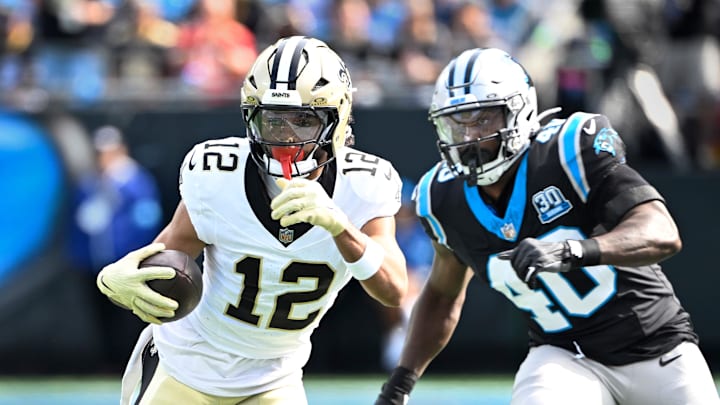 Nov 3, 2024; Charlotte, North Carolina, USA; New Orleans Saints wide receiver Chris Olave (12) with the ball as Carolina Panthers linebacker Charles Harris (40) defends in the first quarter at Bank of America Stadium. Mandatory Credit: Bob Donnan-Imagn Images