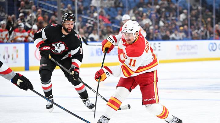 Nov 19, 2025; Buffalo, New York, USA; Calgary Flames center Mikael Backlund (11) shoots the puck as Buffalo Sabres left wing Jordan Greenway (12) defends in the third period at KeyBank Center. Mandatory Credit: Mark Konezny-Imagn Images
