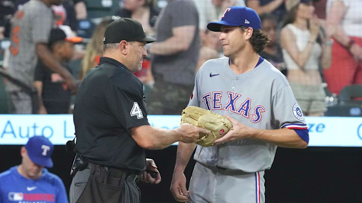 Jun 25, 2025; Baltimore, Maryland, USA; Texas Rangers pitcher Jason DeGrom (48) has his glove checked by umpire Chad Fairchild at the end of the seventh inning against the Baltimore Orioles at Oriole Park at Camden Yards. Mandatory Credit: Mitch Stringer-Imagn Images