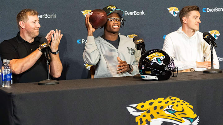 Jacksonville Jaguars Head Coach Liam Coen, left, claps as the Jacksonville Jaguars’ first-round pick, Colorado Buffaloes wide receiver and defensive back Travis Hunter, center, prepares to pass a football during a press conference Friday, March 25, 2025 at Miller Electric Center in Jacksonville, Fla. with General Manager James Gladstone, right. [Doug Engle/Florida Times-Union]