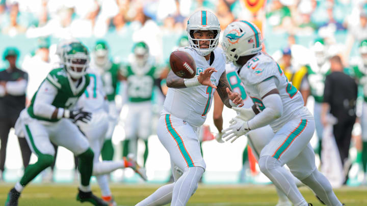 Dec 8, 2024; Miami Gardens, Florida, USA; Miami Dolphins quarterback Tua Tagovailoa (1) tosses the football to running back De'Von Achane (28) against the New York Jets during the second quarter at Hard Rock Stadium. Mandatory Credit: Sam Navarro-Imagn Images