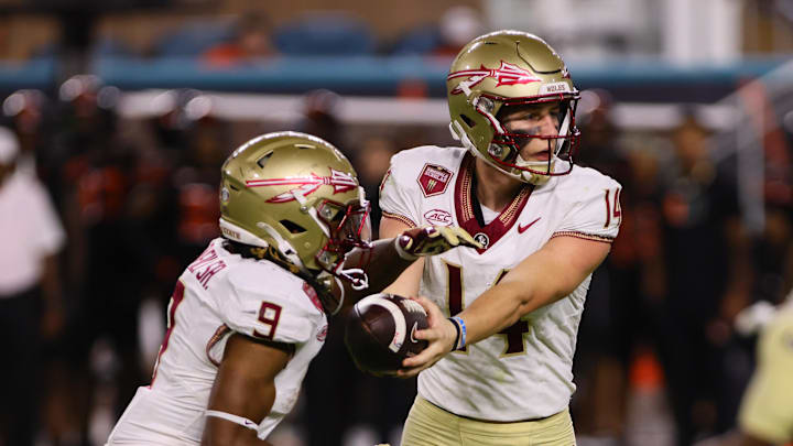Oct 26, 2024; Miami Gardens, Florida, USA; Florida State Seminoles running back Lawrance Toafili (9) takes a handoff from quarterback Luke Kromenhoek (14) against the Miami Hurricanes during the third quarter at Hard Rock Stadium. Mandatory Credit: Sam Navarro-Imagn Images