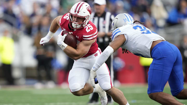Sep 6, 2025; Madison, Wisconsin, USA;  Wisconsin Badgers running back Cade Yacamelli (25) runs the ball against Middle Tennessee Blue Raiders linebacker Muaaz Byard (35) during the second half at Camp Randall Stadium. Mandatory Credit: Kayla Wolf-Imagn Images