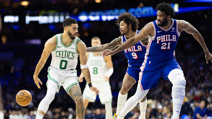 Feb 20, 2025; Philadelphia, Pennsylvania, USA; Boston Celtics forward Jayson Tatum (0) passes the ball back to center Kristaps Porzingis (8) in front of Philadelphia 76ers center Joel Embiid (21) and guard Kelly Oubre Jr. (9) during the second quarter at Wells Fargo Center. Mandatory Credit: Bill Streicher-Imagn Images