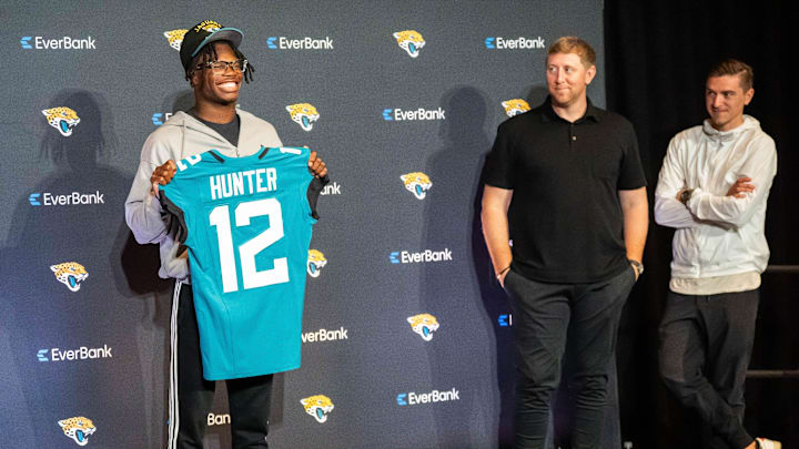 The Jacksonville Jaguars first-round pick, Colorado Buffaloes wide receiver and defensive back Travis Hunter, left, poses with his jersey during a press conference Friday, March 25, 2025 at Miller Electric Center in Jacksonville, Fla. as Head Coach Liam Coen, center and General Manager James Gladstone, right, watch. [Doug Engle/Florida Times-Union]