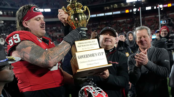 Georgia coach Kirby Smart hands the governor cup to Georgia offensive lineman Tate Ratledge (69) after Georgia won a NCAA college football game against Georgia Tech in overtime in Athens, Ga., on Friday, Nov. 29, 2024. Georgia won 44-42.