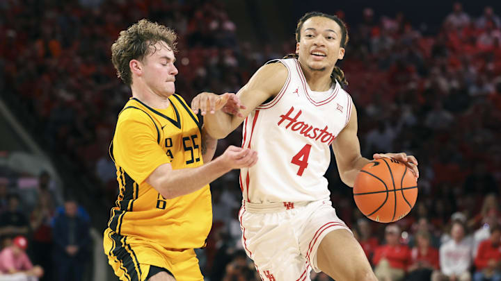 Nov 12, 2025; Houston, Texas, USA; Houston Cougars guard Kingston Flemings (4) drives with the ball as Oakland Golden Grizzlies guard Brody Robinson (55) defends during the first half at Fertitta Center. Mandatory Credit: Troy Taormina-Imagn Images
