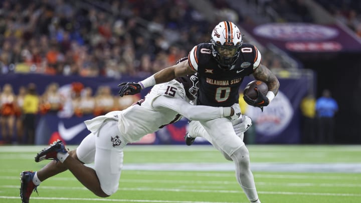 Dec 27, 2023; Houston, TX, USA; Oklahoma State Cowboys running back Ollie Gordon II (0) runs with the ball as Texas A&M Aggies defensive lineman Rylan Kennedy (15) attempts to make a tackle during the third quarter at NRG Stadium. Mandatory Credit: Troy Taormina-USA TODAY Sports