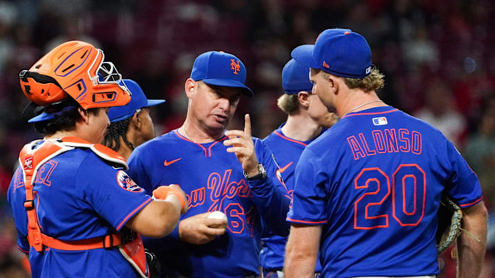 New York Mets manager Carlos Mendoza (64) speaks with players at the pitchers mound in the seventh inning of a MLB game between the Cincinnati Reds and New York Mets, Saturday, Sept. 6, 2025, at Great American Ball Park in downtown Cincinnati. Reds won 6-3.