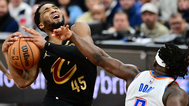 Jan 19, 2026; Cleveland, Ohio, USA; Cleveland Cavaliers guard Donovan Mitchell (45) drives to the basket against Oklahoma City Thunder guard Luguentz Dort (5) during the second half at Rocket Arena. Mandatory Credit: Ken Blaze-Imagn Images