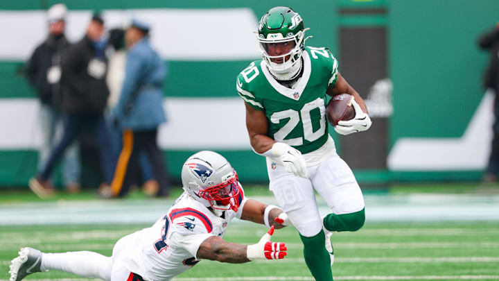 Dec 28, 2025; East Rutherford, New Jersey, USA; New York Jets running back Breece Hall (20) carries the ball asNew England Patriots linebacker K'Lavon Chaisson (44) pursues during the first half at MetLife Stadium. Mandatory Credit: Vincent Carchietta-Imagn Images
