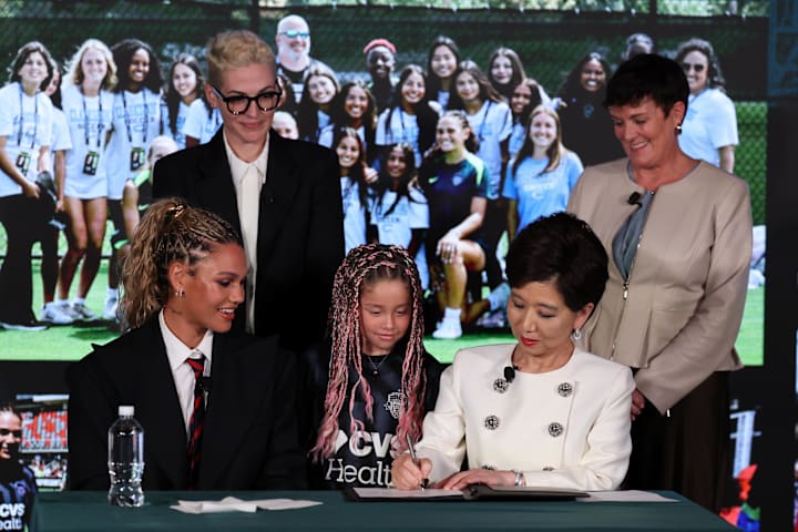 Trinity Rodman ของ Washington Spirit สังเกตการณ์เจ้าของทีม Michele Kang (ด้านหน้าขวา) ลงนามการต่อสัญญา