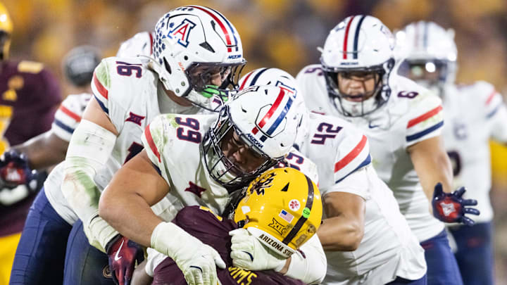 Nov 28, 2025; Tempe, Arizona, USA; Arizona State Sun Devils quarterback Jeff Sims (2) is tackled by Arizona Wildcats defensive lineman Mays Pese (99) in the second half during the 99th Territorial Cup at Mountain America Stadium. Mandatory Credit: Mark J. Rebilas-Imagn Images