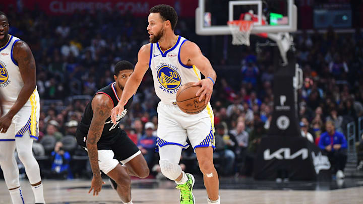 Golden State Warriors guard Stephen Curry (30) moves the ball ahead of Los Angeles Clippers forward Paul George (13) during the first half at Crypto.com Arena. Mandatory Credit: Gary A. Vasquez-Imagn Images