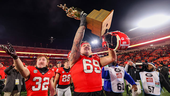 Nov 29, 2024; Athens, Georgia, USA; Georgia Bulldogs offensive lineman Tate Ratledge (69) holds the Governor’s Cup with running back Cash Jones (32) after a victory over the Georgia Tech Yellow Jackets in eight overtimes at Sanford Stadium. Mandatory Credit: Brett Davis-Imagn Images Nov 29, 2024; Athens, Georgia, USA; Georgia Bulldogs offensive lineman Tate Ratledge (69) holds the Governor’s Cup with running back Cash Jones (32) after a victory over the Georgia Tech Yellow Jackets in eight overtimes at Sanford Stadium. Mandatory Credit: Brett Davis-Imagn Images