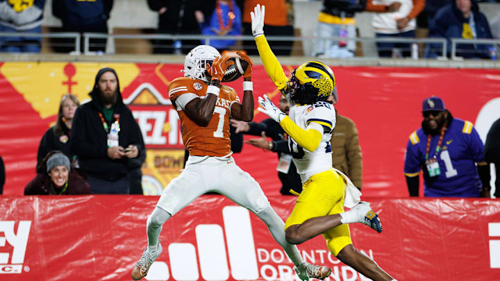 Dec 31, 2025; Orlando, FL, USA; Texas Longhorns wide receiver Kaliq Lockett (7) makes a catch over Michigan Wolverines defensive back Jyaire Hill (20) for touchdown during the second half at Camping World Stadium. Mandatory Credit: Matt Pendleton-Imagn Images