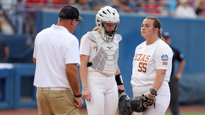 Texas coach Mike White talks with Texa pitcher Mac Morgan (55) and Reese Atwood (14) during Game 2 of the NCAA softball Women's College World Series Championship Series game between the Oklahoma Sooners (OU) and Texas Longhorns at Devon Park in Oklahoma City, Thursday, June 6, 2024. Oklahoma won 8-4.
