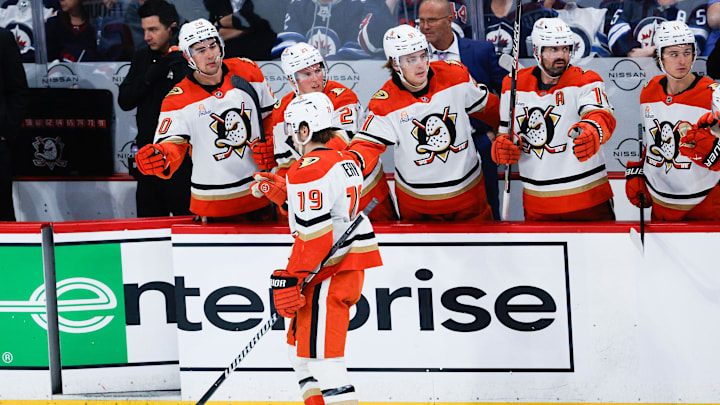 Apr 16, 2025; Winnipeg, Manitoba, CAN;  Anaheim Ducks forward Troy Terry (19) is congratulated by his team mates on his goal against Winnipeg Jets goalie Connor Hellebuyck (37) during the third period at Canada Life Centre. Mandatory Credit: Terrence Lee-Imagn Images