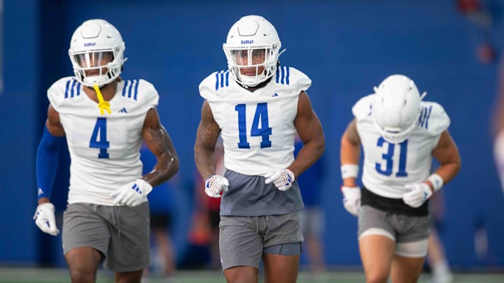 Kansas safety players, from left, redshirt senior Marvin Grant (4), redshirt junior Jalen Dye (14), and redshirt junior Landon Nelson (31) run to the next station during an indoor practice Wednesday, July 31.