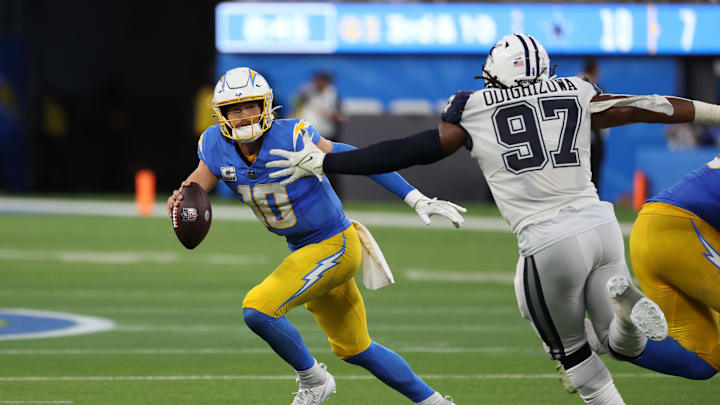 Oct 16, 2023; Inglewood, California, USA;  Los Angeles Chargers quarterback Justin Herbert (10) runs away from Dallas Cowboys defensive tackle Osa Odighizuwa (97) during the third quarter at SoFi Stadium. Mandatory Credit: Kiyoshi Mio-Imagn Images
