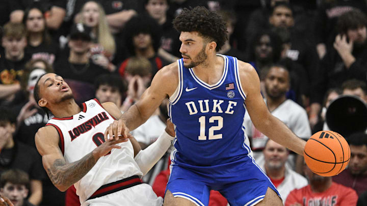 Jan 6, 2026; Louisville, Kentucky, USA;  Duke Blue Devils forward Cameron Boozer (12) charges into Louisville Cardinals forward Khani Rooths (9) during the second half at KFC Yum! Center. Mandatory Credit: Jamie Rhodes-Imagn Images