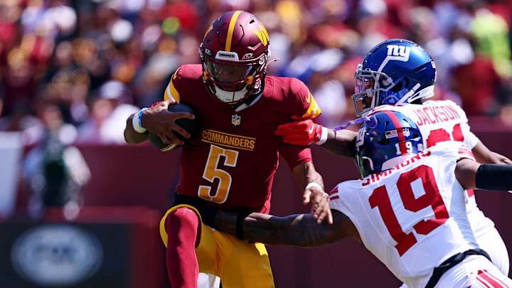 Sep 15, 2024; Landover, Maryland, USA; Washington Commanders quarterback Jayden Daniels (5) runs the ball against New York Giants linebacker Isaiah Simmons (19) during the first quarter at Commanders Field. Mandatory Credit: Peter Casey-Imagn Images