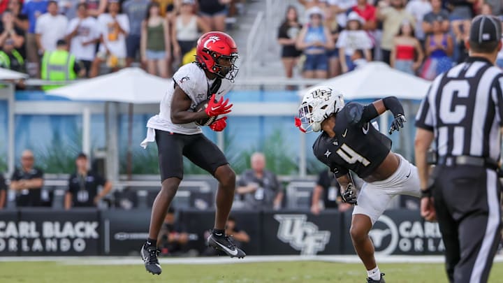 Oct 12, 2024; Orlando, Florida, USA; Cincinnati Bearcats wide receiver Tony Johnson (0) catches a pass in front of UCF Knights defensive back Braeden Marshall (4) during the second half at FBC Mortgage Stadium. Mandatory Credit: Mike Watters-Imagn Images