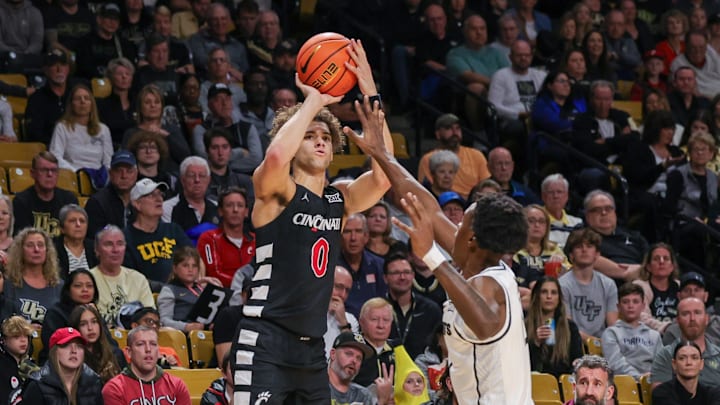 Feb 17, 2024; Orlando, Florida, USA; Cincinnati Bearcats guard Dan Skillings Jr. (0) shoots the ball against UCF Knights forward Marchelus Avery (13) during the first half at Addition Financial Arena. Mandatory Credit: Mike Watters-Imagn Images