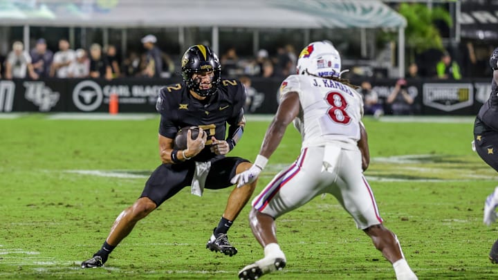 Oct 4, 2025; Orlando, Florida, USA; UCF Knights quarterback Tayven Jackson (2) runs the ball in front of Kansas Jayhawks linebacker Jon Jon Kamara (8) during the second quarter at FBC Mortgage Stadium. Mandatory Credit: Mike Watters-Imagn Images