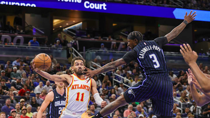 Apr 8, 2025; Orlando, Florida, USA; Atlanta Hawks guard Trae Young (11) passes the ball around Orlando Magic guard Kentavious Caldwell-Pope (3) during the first quarter at Kia Center. Mandatory Credit: Mike Watters-Imagn Images